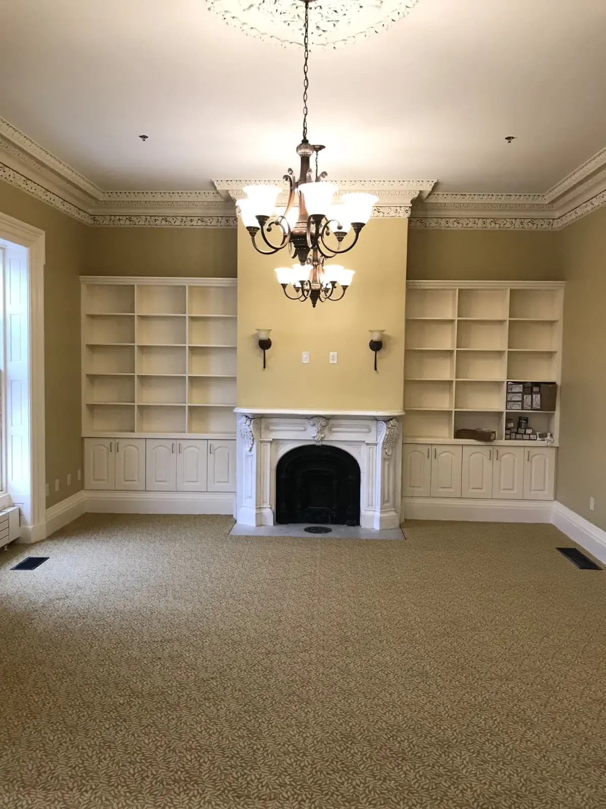 Historic room with painted built-ins, fireplace, and detailed molding