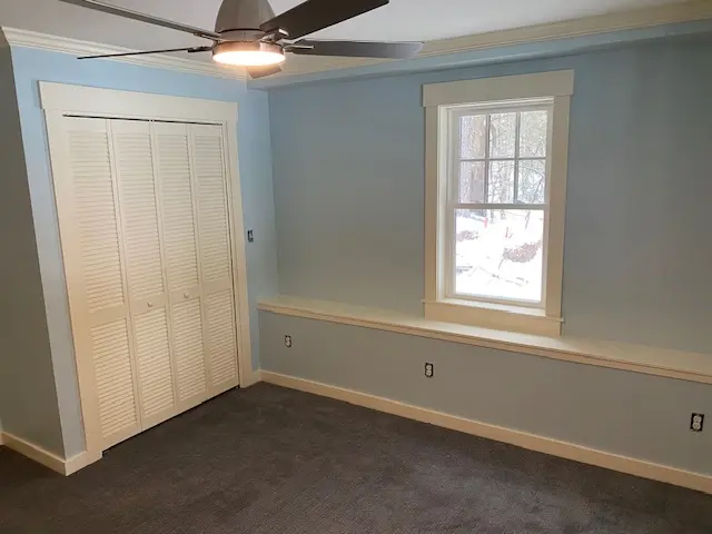 Soft blue residential bedroom with white trim